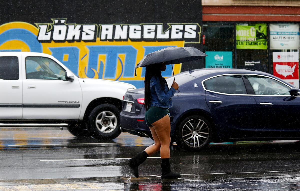 A woman walks in the rain along Figueroa Street in South Los Angeles.