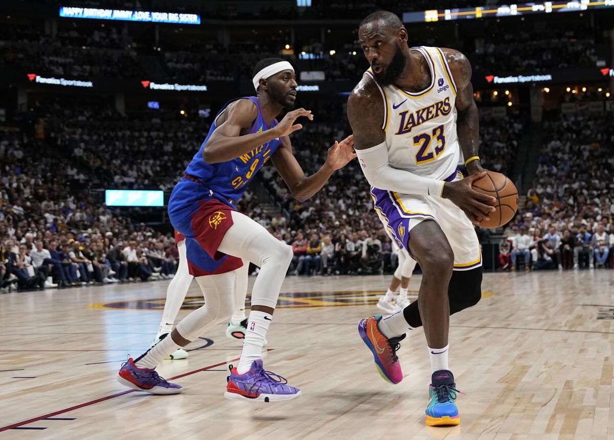 Lakers forward LeBron James tries to protect the ball as he's pressured by Nuggets forward Justin Holiday on Saturday.