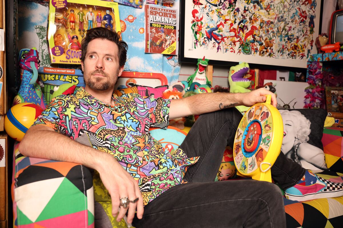 An art director sits among brightly colored toys and collectibles. 