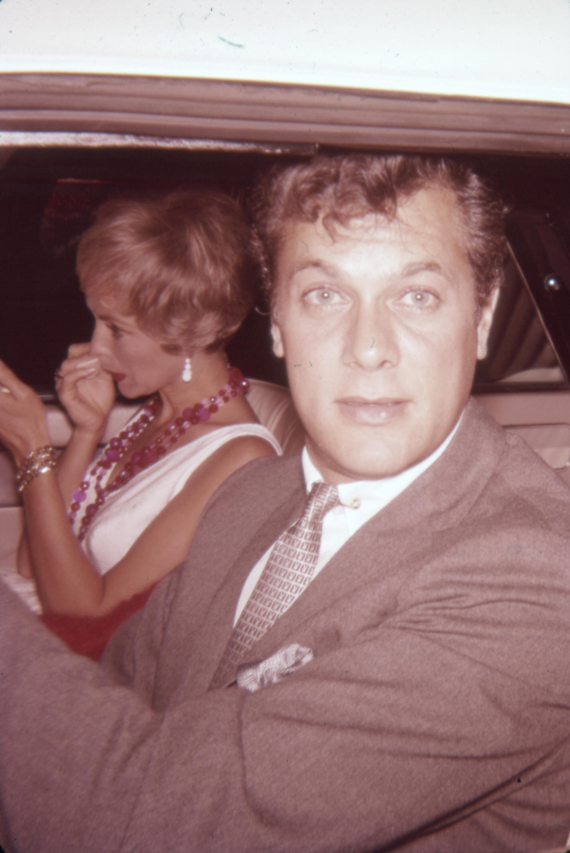 A well-dressed man and woman seated in a car.