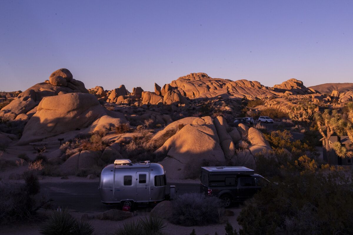 A camper trailer has a sunrise view over the rocks in Joshua Tree National Park.