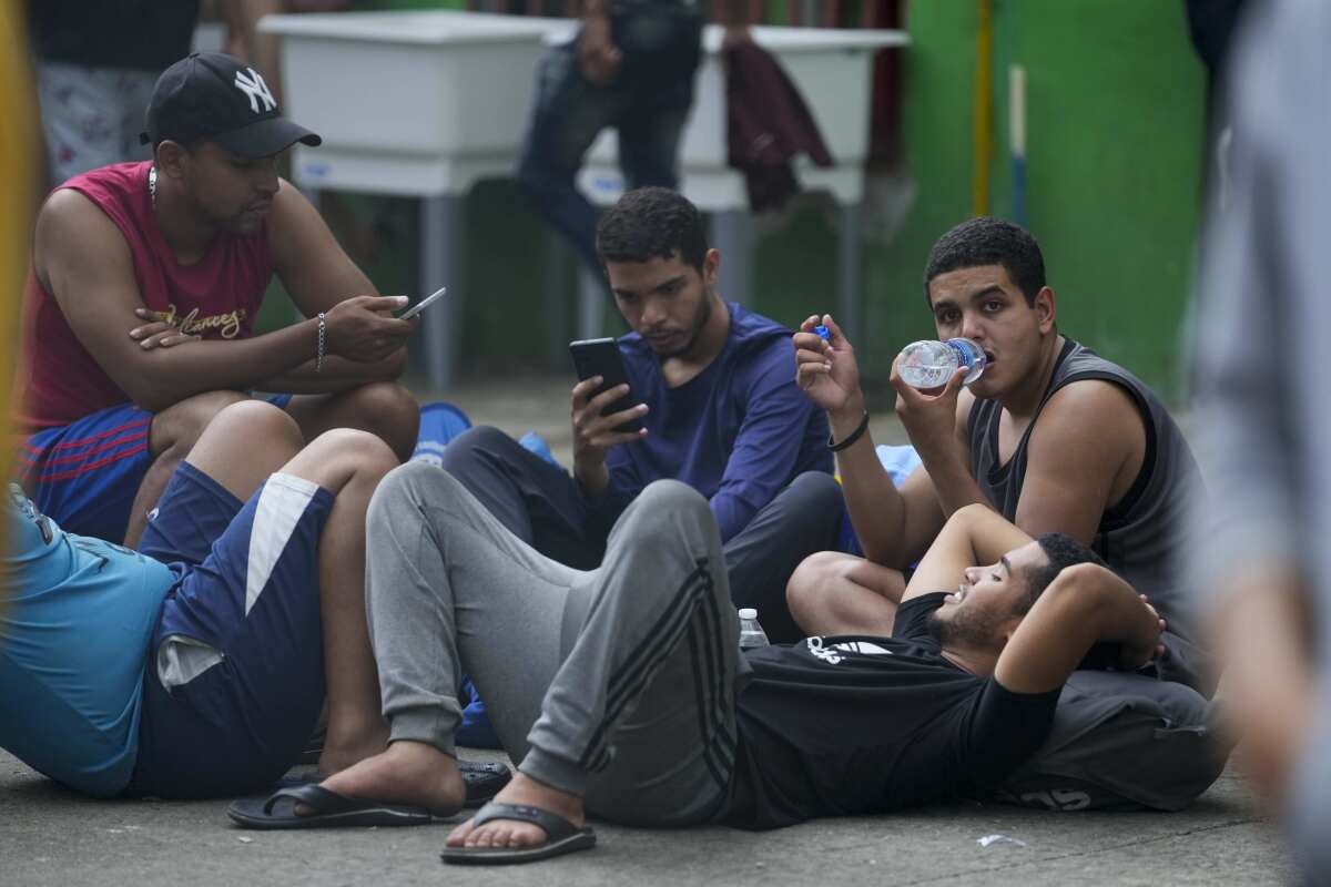 Migrantes venezolanos revisan sus teléfonos móviles mientras esperan en un albergue temporal en Ciudad de Panamá