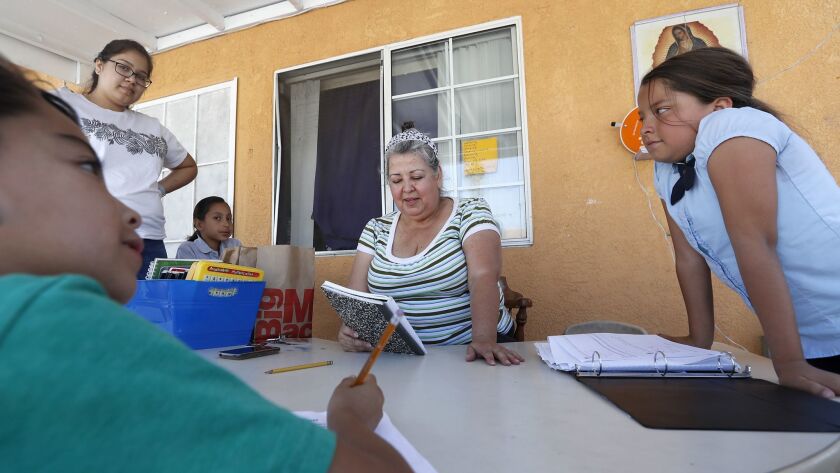 Juana Juaregui goes over homework with kids who congregate at her East Los Angeles home after school every day. J