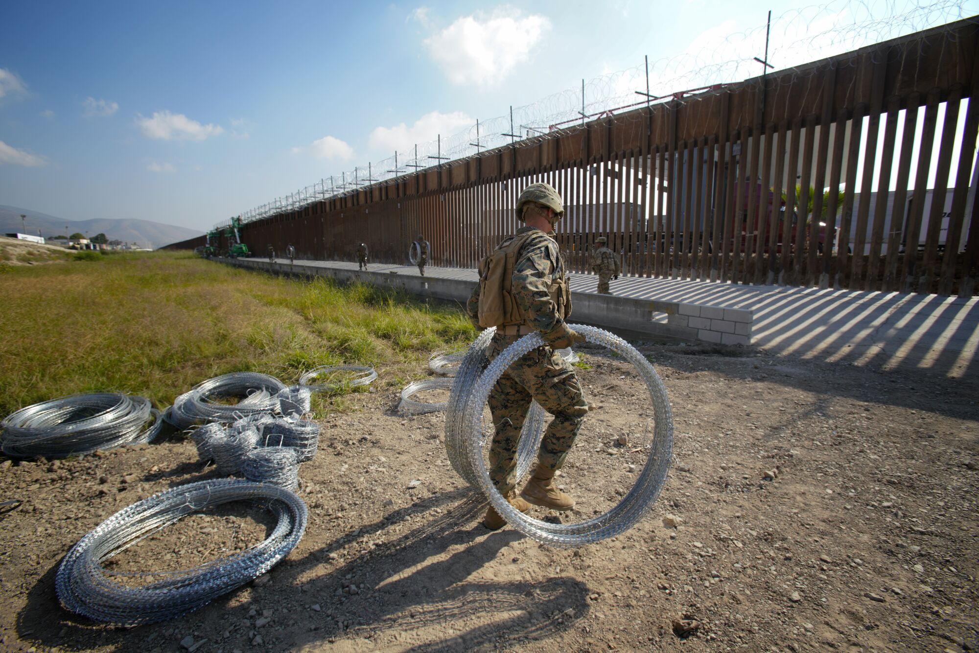 A U.S. military service member carries concertina wire by the barrier at the U.S.-Mexico border in San Diego 