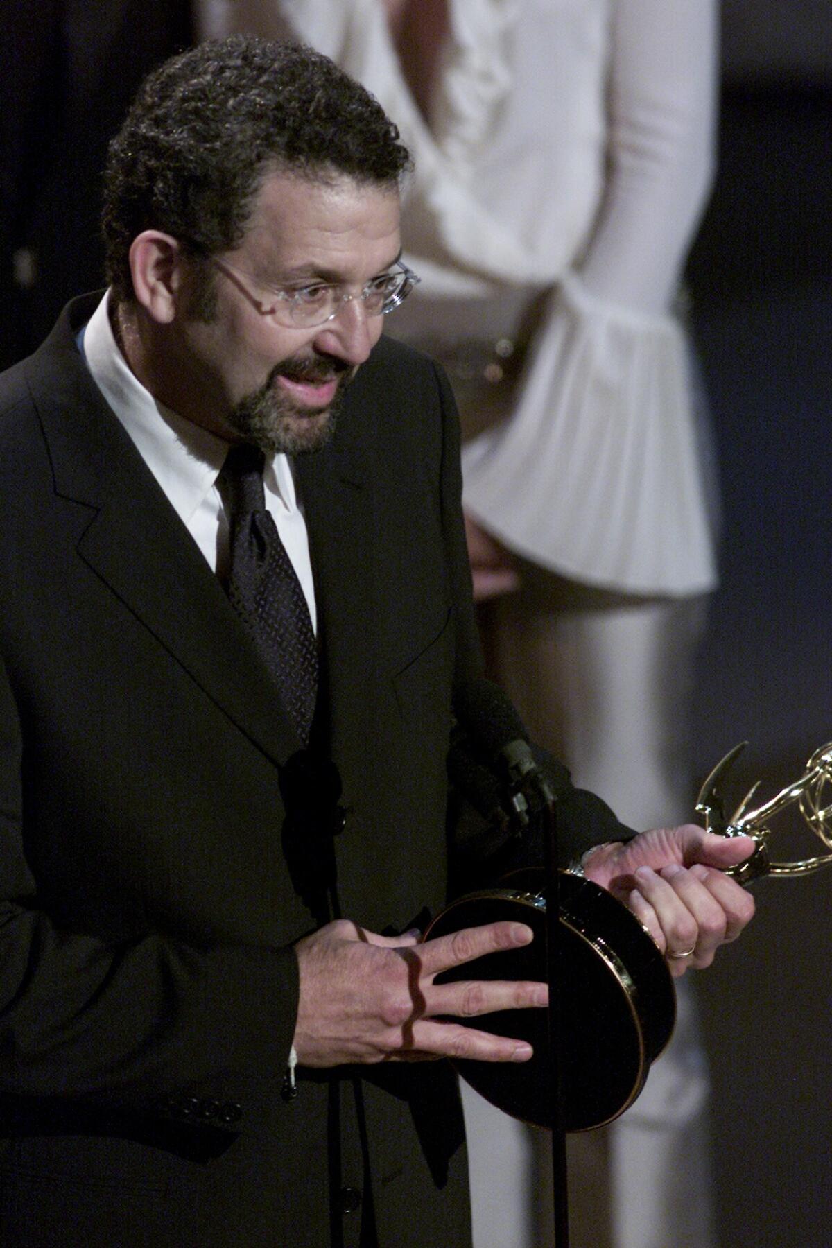 Thomas Schlamme holds his Emmy as he delivers an acceptance speech onstage. 