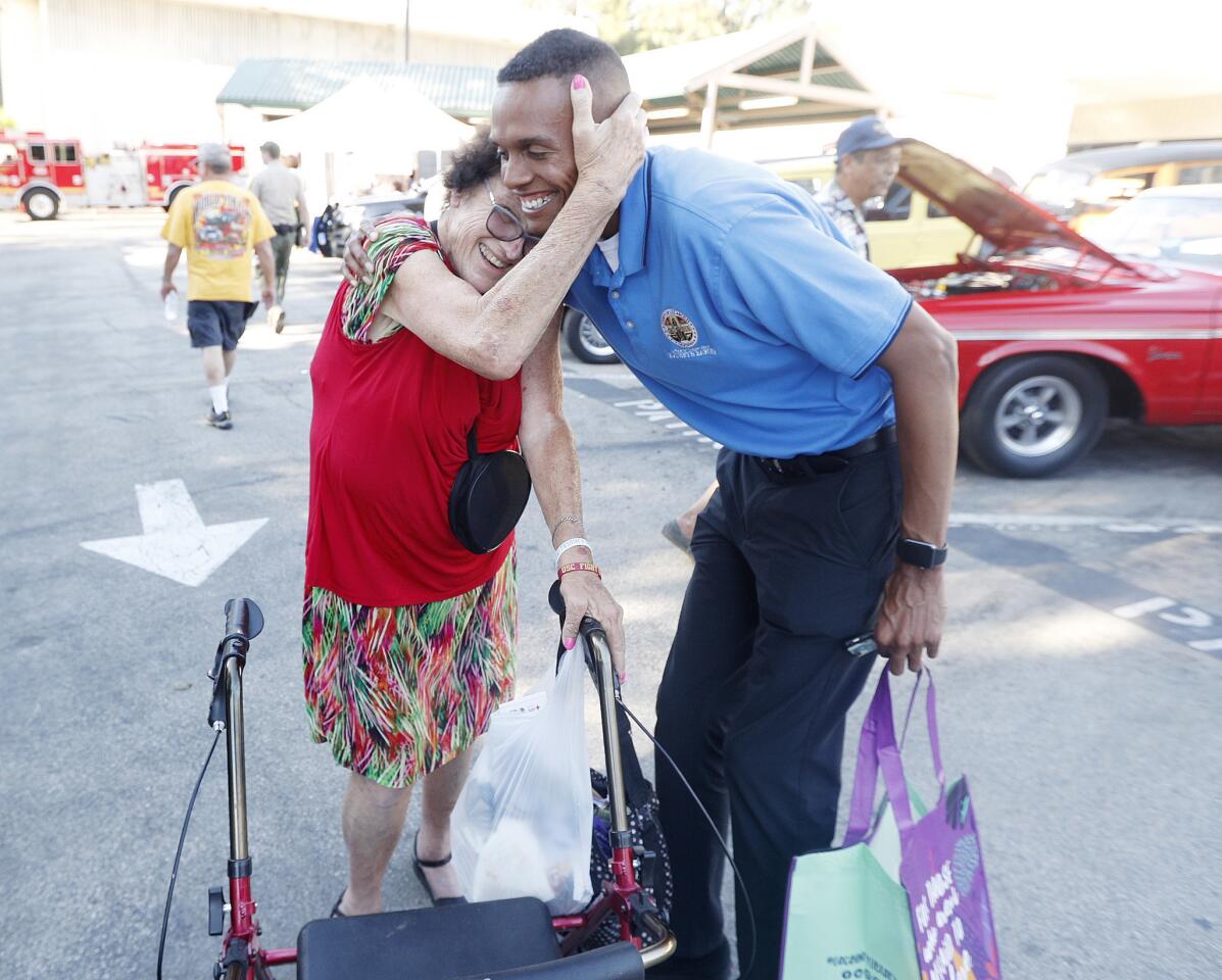Harriet Hammons, of the La Canada Flintridge Chamber of Commerce, hugs Kathryn Barger Assistant Field Deputy Christian Daly at the Crescenta Valley Sheriff's Station which is participating in National Night Out on Tuesday, August 7, 2018. The event included a car show and a tour of the station.