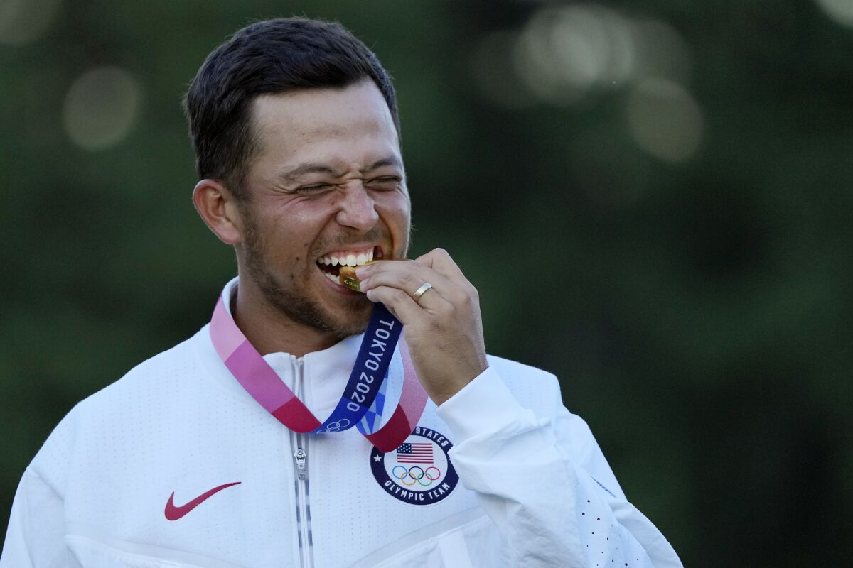 Xander Schauffele bites his gold medal at the men's golf tournament at Kasumigaseki Country Club.