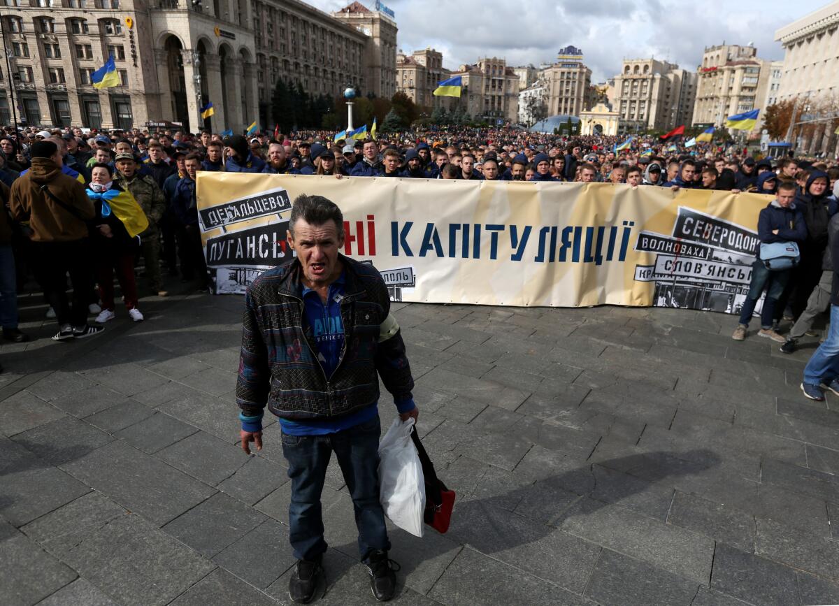 "No to Capitulation," reads a banner held by demonstrators in downtown Kyiv, Ukraine, on Sunday.