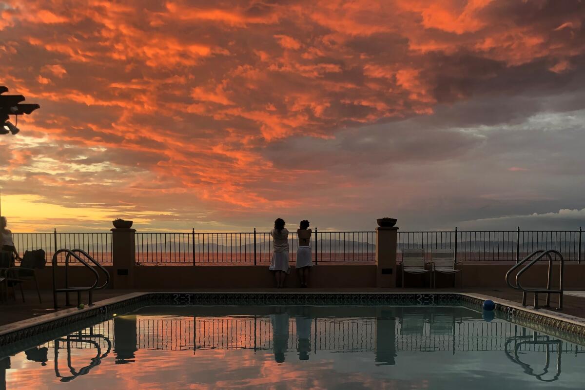 Wide view of ocean under pink clouds, with reflecting pool in foreground.