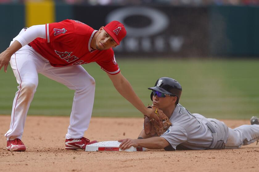 Seattle Mariners' Norichika Aoki, right, steals second as Angels shortstop Andrelton Simmons applies a late tag during the ninth inning on Sunday.
