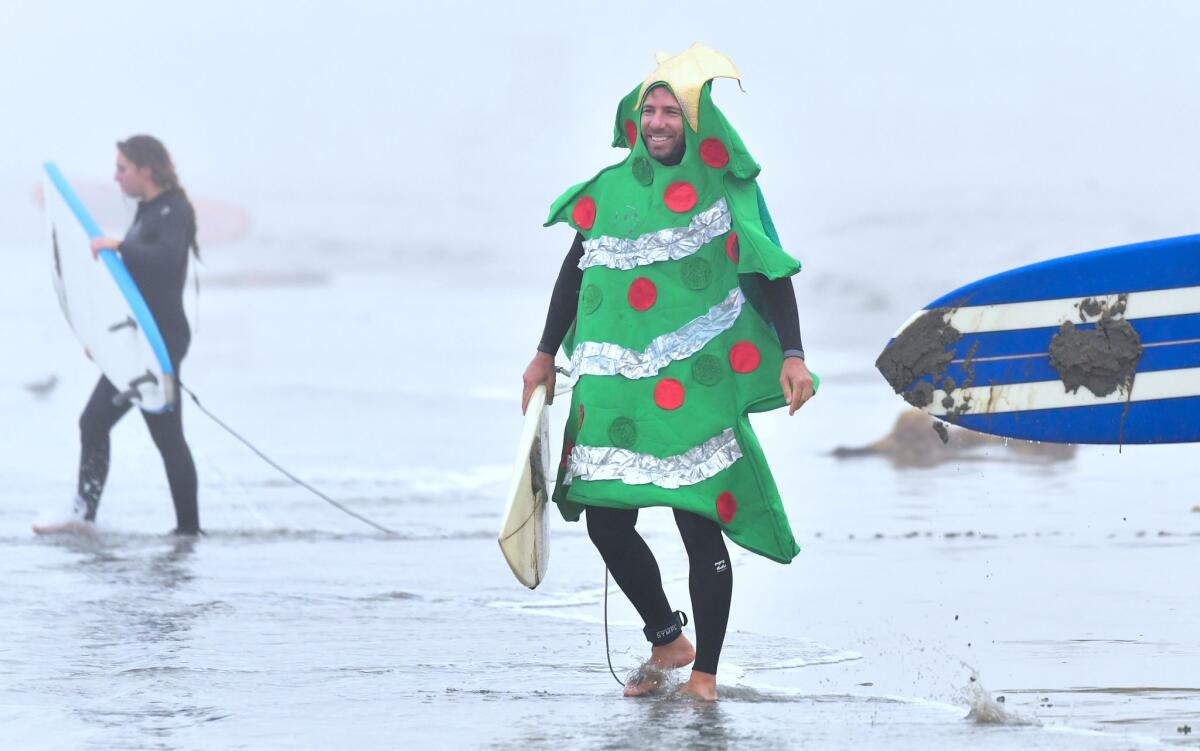 A surfer dressed as a Christmas tree prepares to hit the waves at Blackies beach in Newport Beach in 2018.