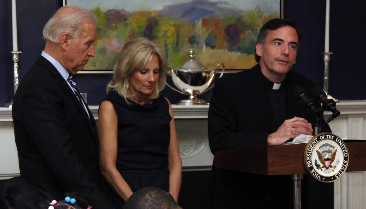 Joe Biden and his wife, Jill, bow their heads next to a priest.