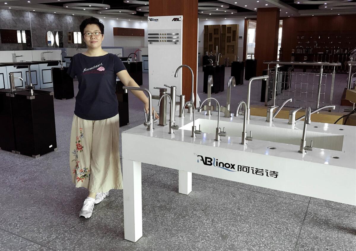 Kate Liang, president of Guangdong ABLinox Sanitaryware company, stands next to models of the kitchen and bathroom fittings her company makes for Chinese and overseas customers. Americans account for one-fifth of her customers, Liang said.