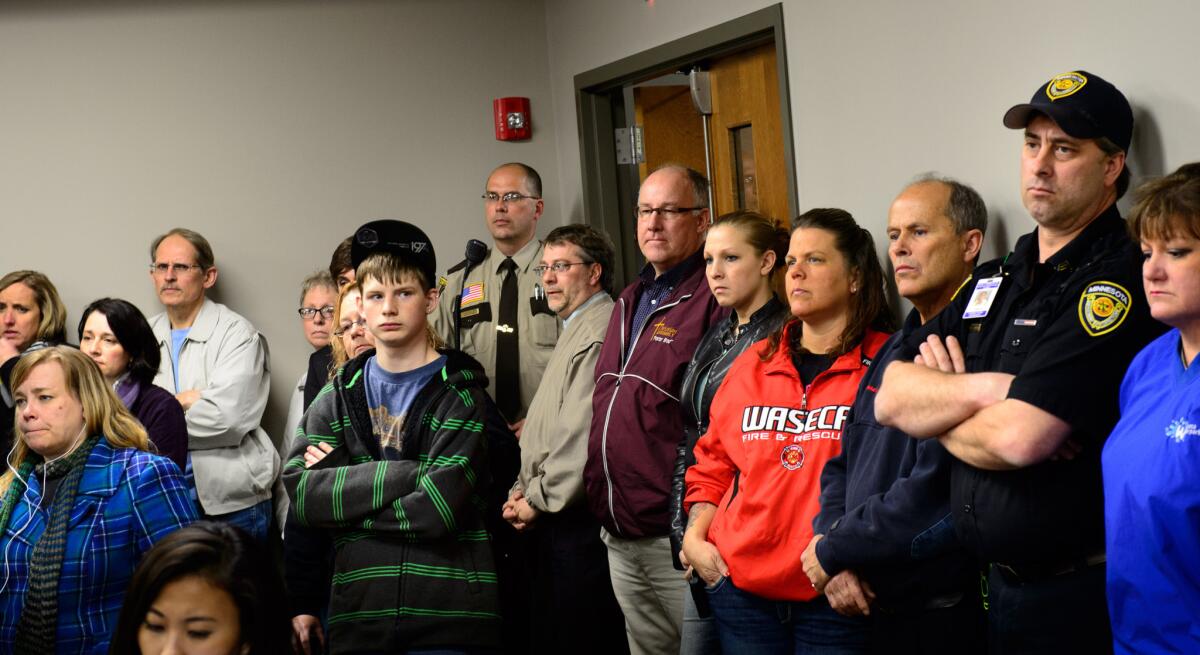 Students, parents and community members stand in the back of the room to listen as Waseca police and school officials speak at a news conference about the 17-year-old arrested in a plot to kill his family and massacre students.