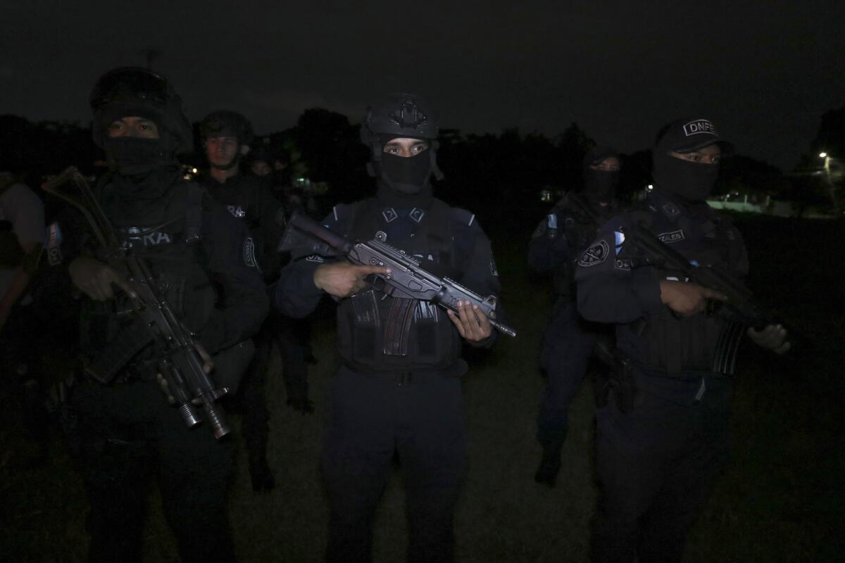 A group of officers in dark uniforms wielding assault weapons