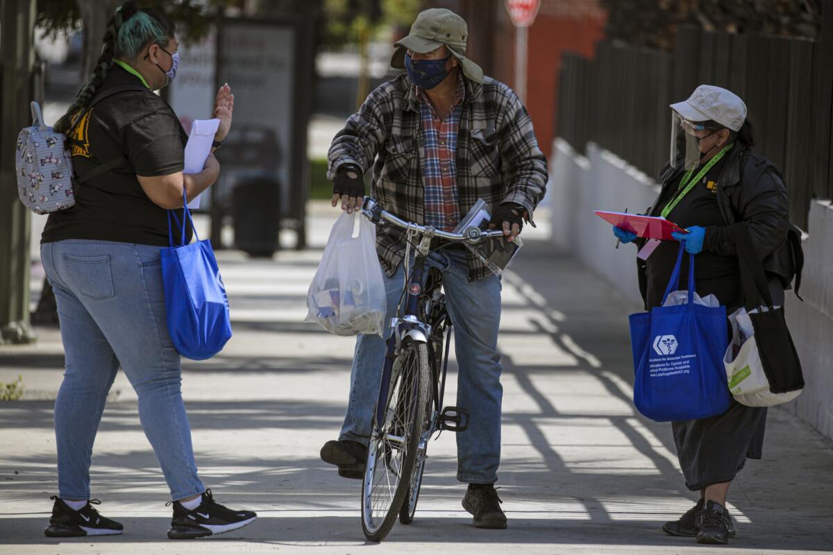 Two women talk to a man on a bicycle.