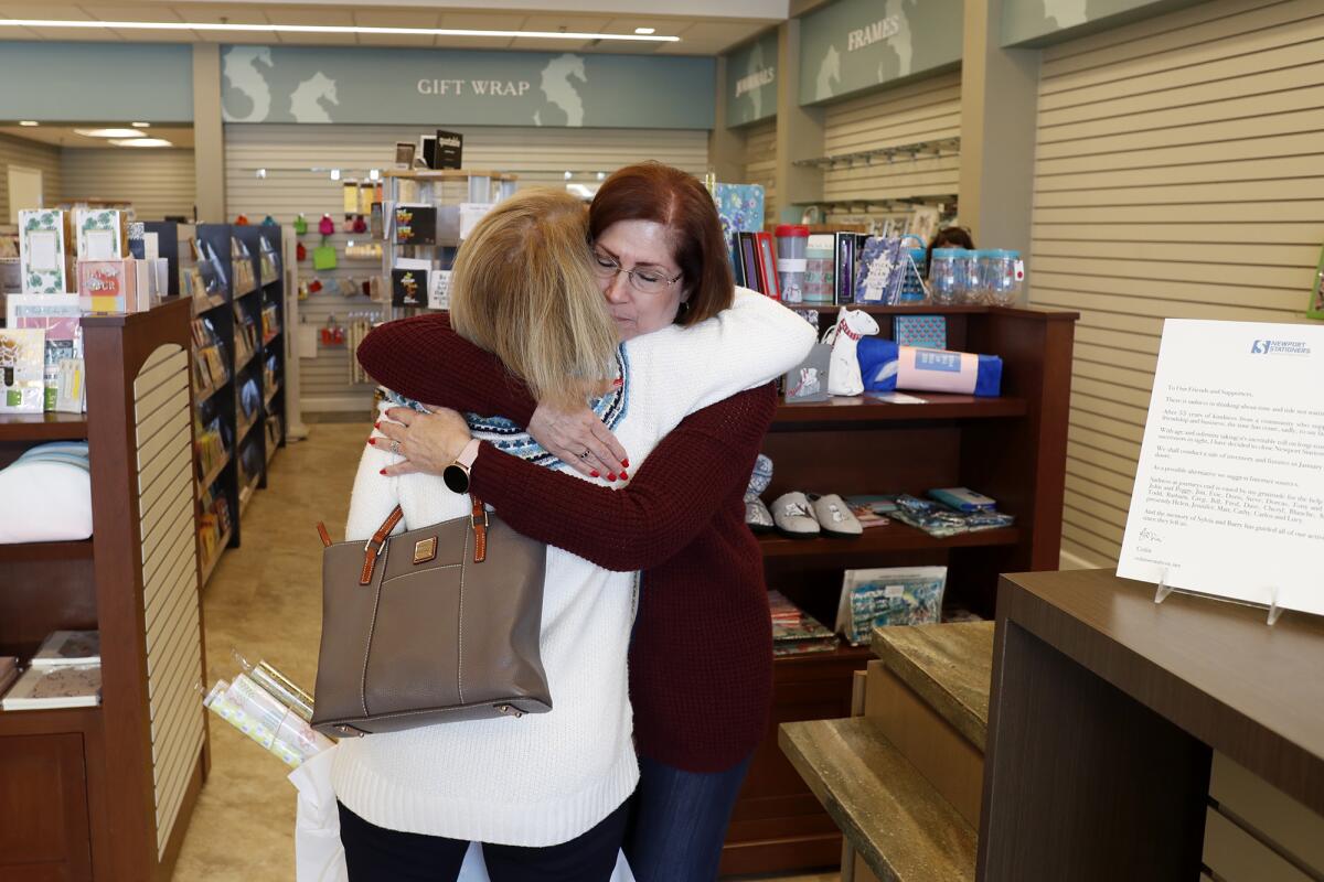 Newport Stationers co-manager Peggy Tackman, right, shares a hug Friday with Lynda Badum, a customer since 1983.