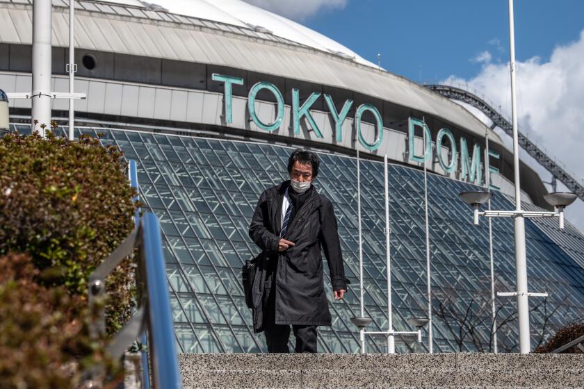 TOKYO, JAPAN - FEBRUARY 27: A man wearing a face mask walks past Tokyo Dome where a number of events including pop concerts have been cancelled because of concerns over the Covid-19 virus, on February 27, 2020 in Tokyo, Japan. A growing number of events and sporting fixtures are being cancelled or postponed around Japan while some businesses are asking their employees to work from home and some schools are closing as Covid-19 cases continue to increase and concerns mount over the possibility that the epidemic will force the postponement or even cancellation of the Tokyo Olympics. (Photo by Carl Court/Getty Images)