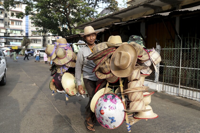 A vender carries bamboo hats for sale at a market in Yangon, Myanmar Saturday, March 21, 2020. About 1.6 million jobs were lost in Myanmar in 2021, the International Labor Organization, said in a report Friday, Jan. 28, 2022, with women suffering the biggest setbacks as work in factories, tourism and construction dwindled amid the pandemic and a military takeover. (AP Photo/Thein Zaw)