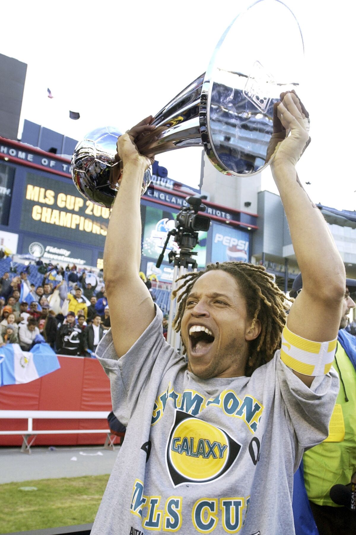 FILE - Los Angeles Galaxy captain Cobi Jones shouts as he holds the MLS Cup aloft after they defeated the New England Revolution, 1-0, in overtime at Gillette Stadium in Foxboro, Mass., in this Sunday Oct. 20, 2002, file photo. Jones, one of the league's original players who spent his entire 11-year career with the Galaxy, was named one of the MLS 25 Greatest on Wednesday, Dec. 9, 2020. His favorite moment in his 11 MLS seasons is winning that first league title with the Galaxy. (AP Photo/Elise Amendola, File)