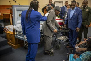 Pirate Joe Harris Sr. is supported by friends and relatives as he views the body of his father during a memorial service.