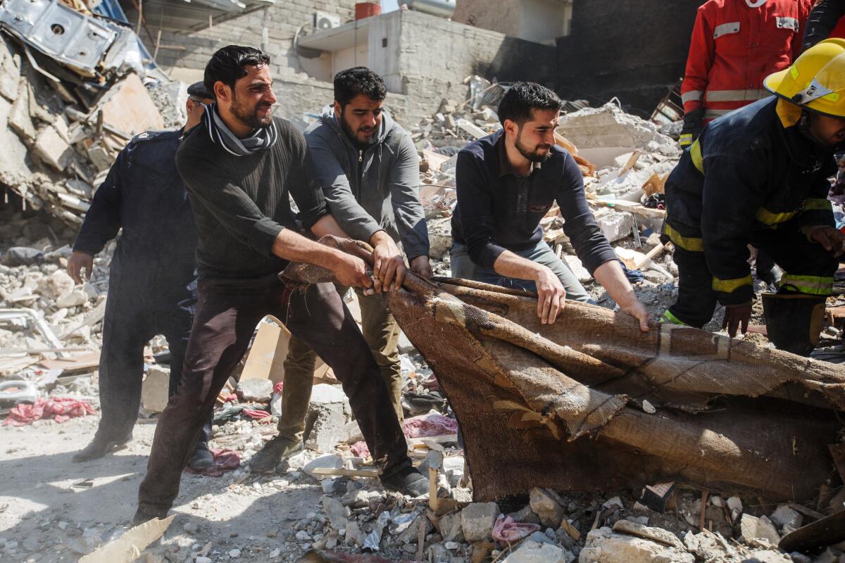 Family members help Iraqi Civil Defense members pull corpses from beneath the rubble in Mosul after airstrikes killed dozens of civilians. (Marcus Yam / Los Angeles Times)