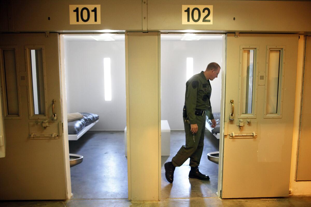 A man in uniform looks inside a prison cell
