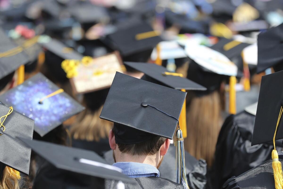 Students in caps and gowns at a graduation.