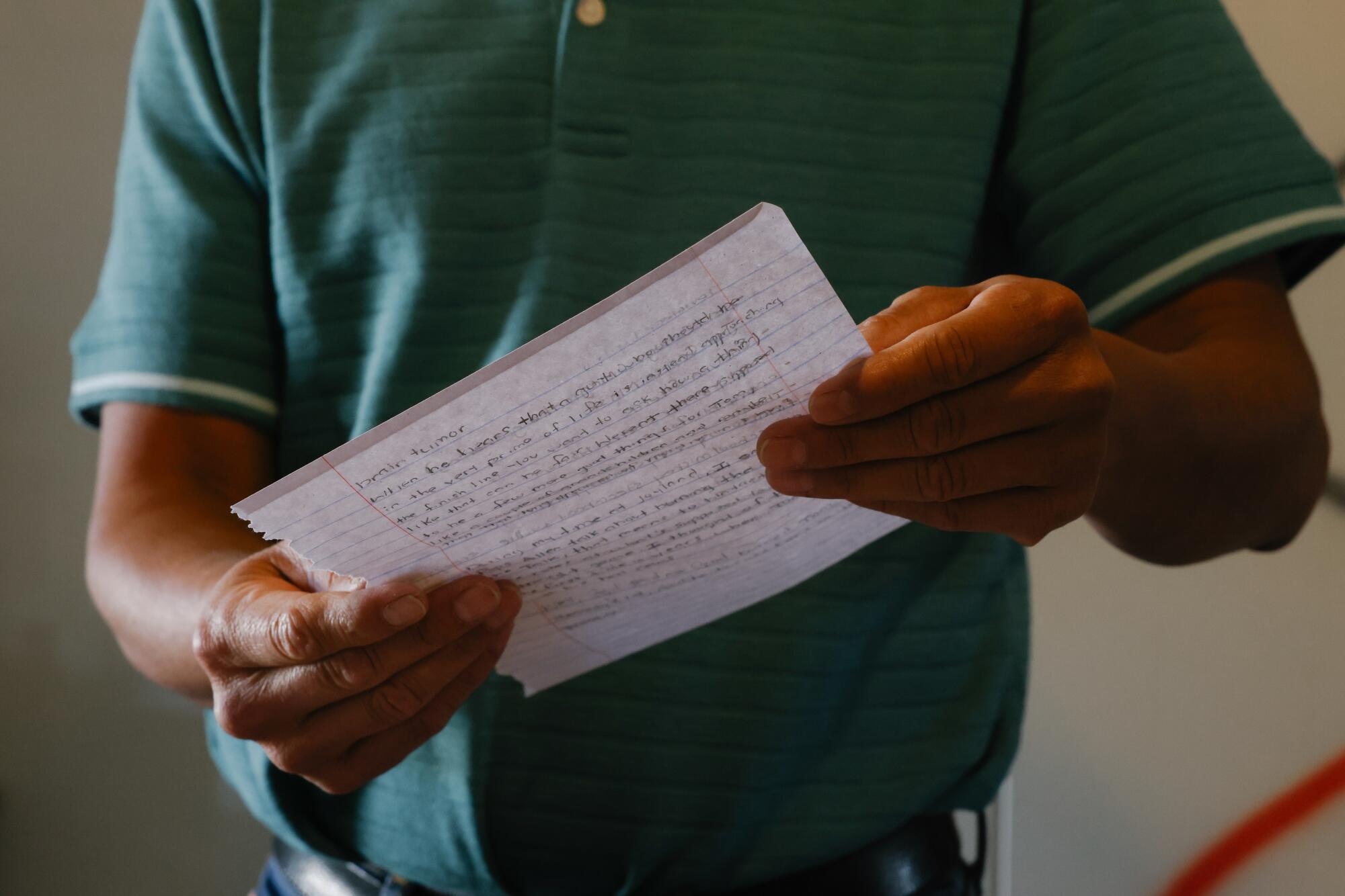 The torso of a person holding a handwritten letter in both hands