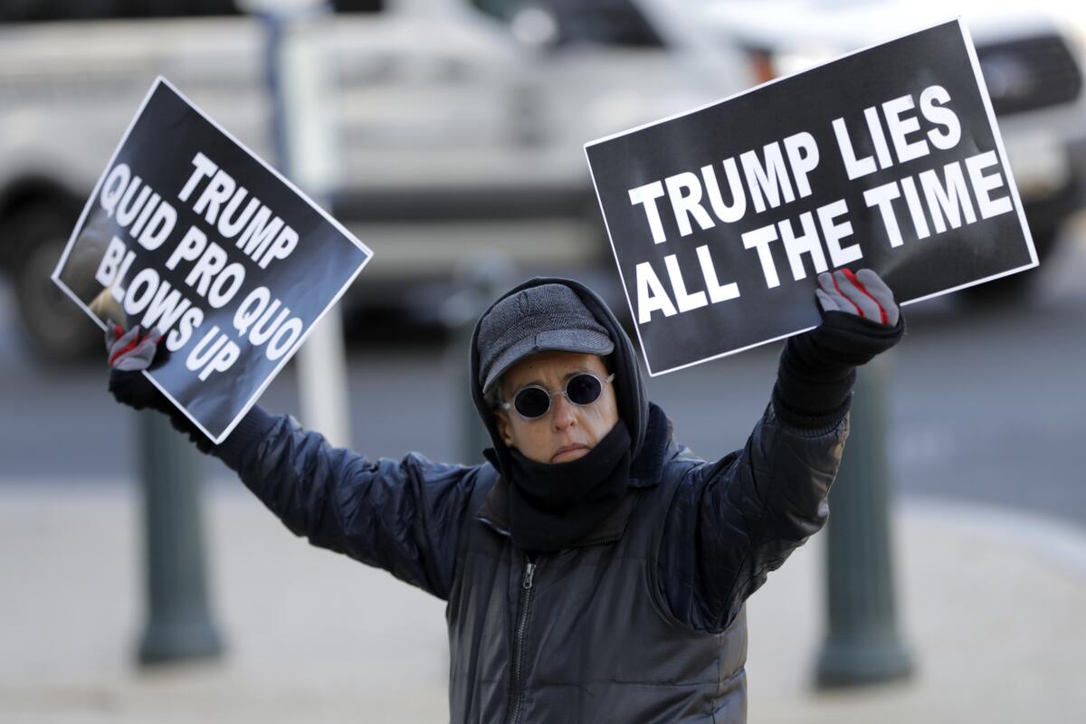 Un manifestante sostiene carteles de protesta contra el presidente Donald Trump afuera de la sede del Congreso, en Washington el 13 de noviembre de 2019, al iniciar las audiencias públicas sobre la investigación de juicio político al mandatario. (AP Foto/Julio Cortez)