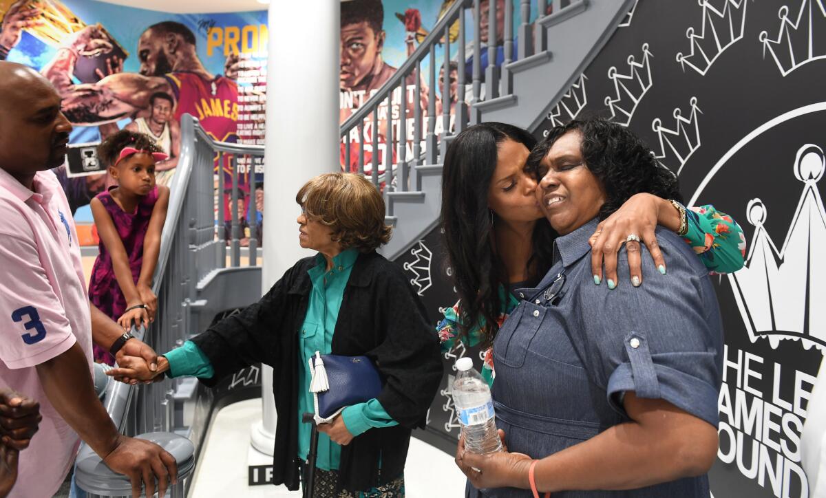 Intervention specialist Angela Whorton kisses her mother, Karla Burham, as other family members look on inside the I Promise School on July 29.