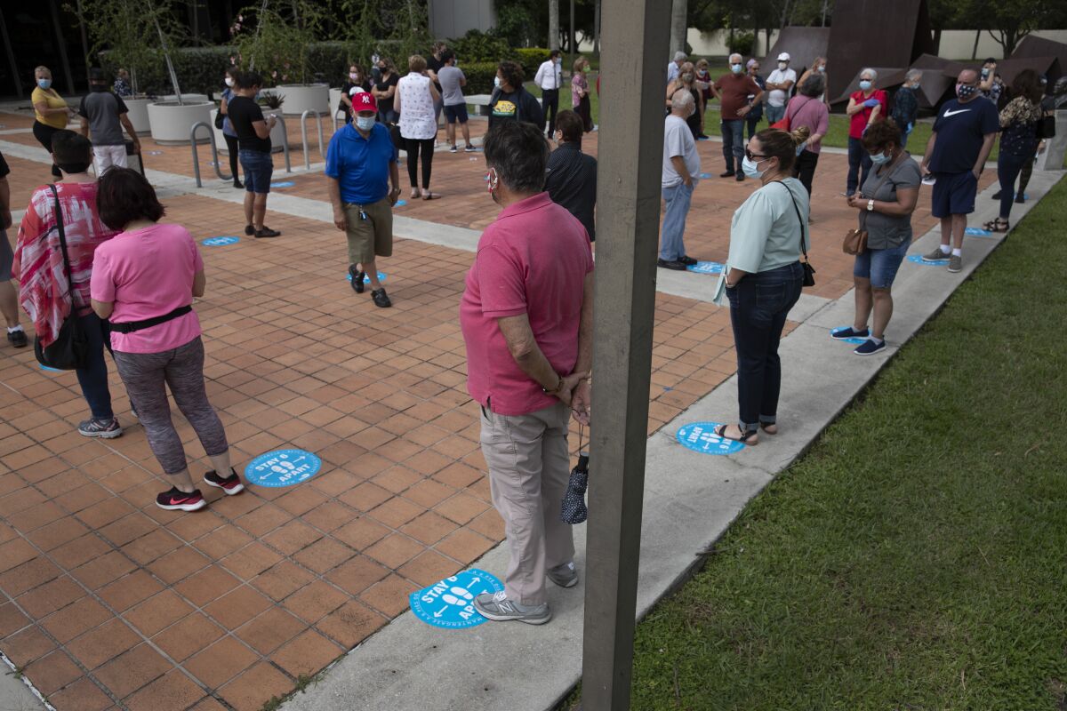 Early voters wait to cast their ballots Monday at a library in Westchester, Fla.
