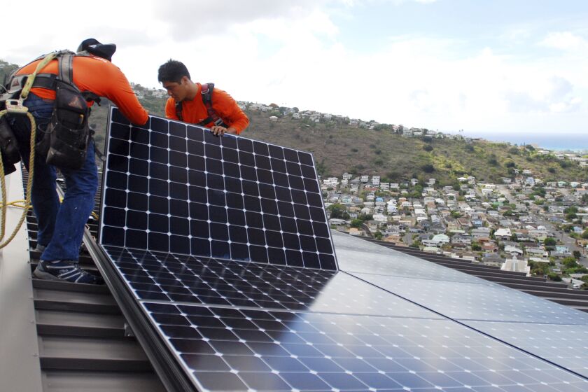 FILE - In this July 8, 2016, file photo, Radford Takashima, left, installer for RevoluSun, and lead installer Dane Hew Len, right, place solar panels on a roof in Honolulu. If you have the cash, most experts agree buying a solar system outright is a better investment than leasing or taking out a loan. Customers should check electric bills to estimate monthly energy use when deciding what size system to buy, and calculate federal or state incentives. (AP Photo/Cathy Bussewitz, File)