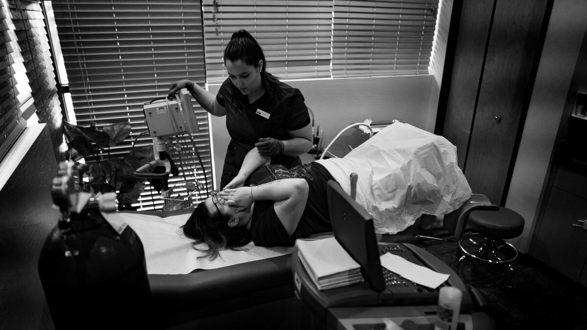 A nurse comforts a patient after an abortion procedure at a clinic in Phoenix. The clinic is another that depends on doctors who travel from California. (Gina Ferazzi / Los Angeles Times)