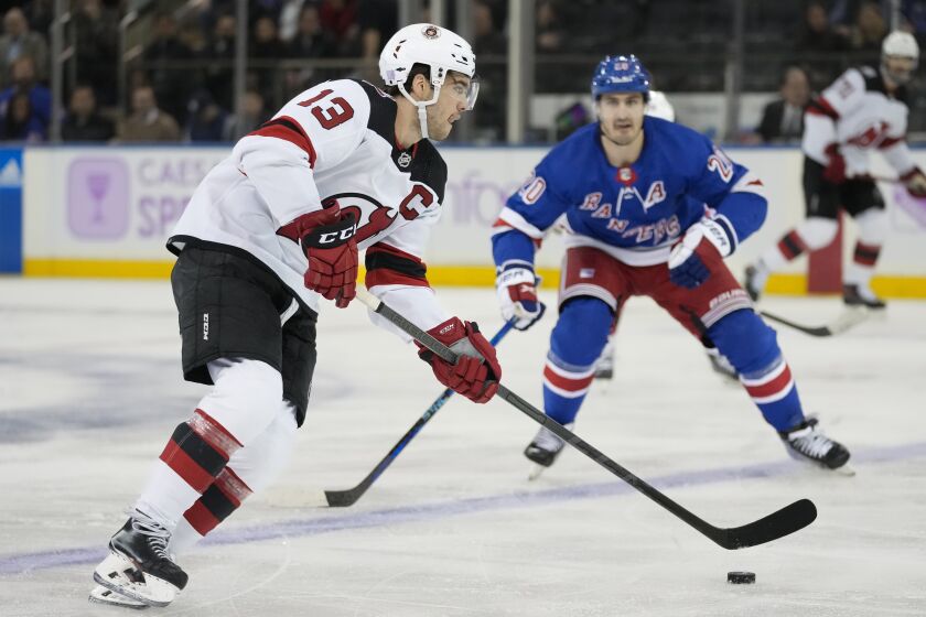 New Jersey Devils center Nico Hischier (13) looks to pass against New York Rangers left wing Chris Kreider (20) in the second period of an NHL hockey game, Monday, Nov. 28, 2022, in New York. (AP Photo/John Minchillo)