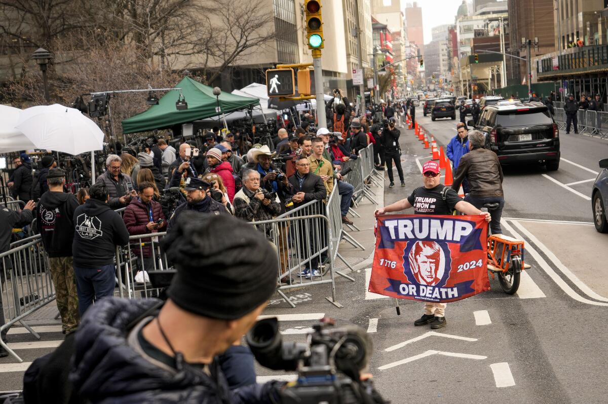 Supporters of former President Trump gather on a street corner, one with a sign reading "Trump or death"