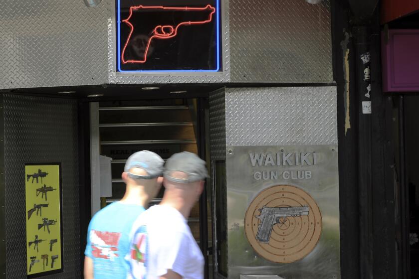FILE - People walk past a gun club in Honolulu, June, 23, 2022. Honolulu is agreeing to approve or deny applications to carry concealed guns within four months in response to a lawsuit by residents who faced delays of more than a year. (AP Photo/Marco Garcia, File)