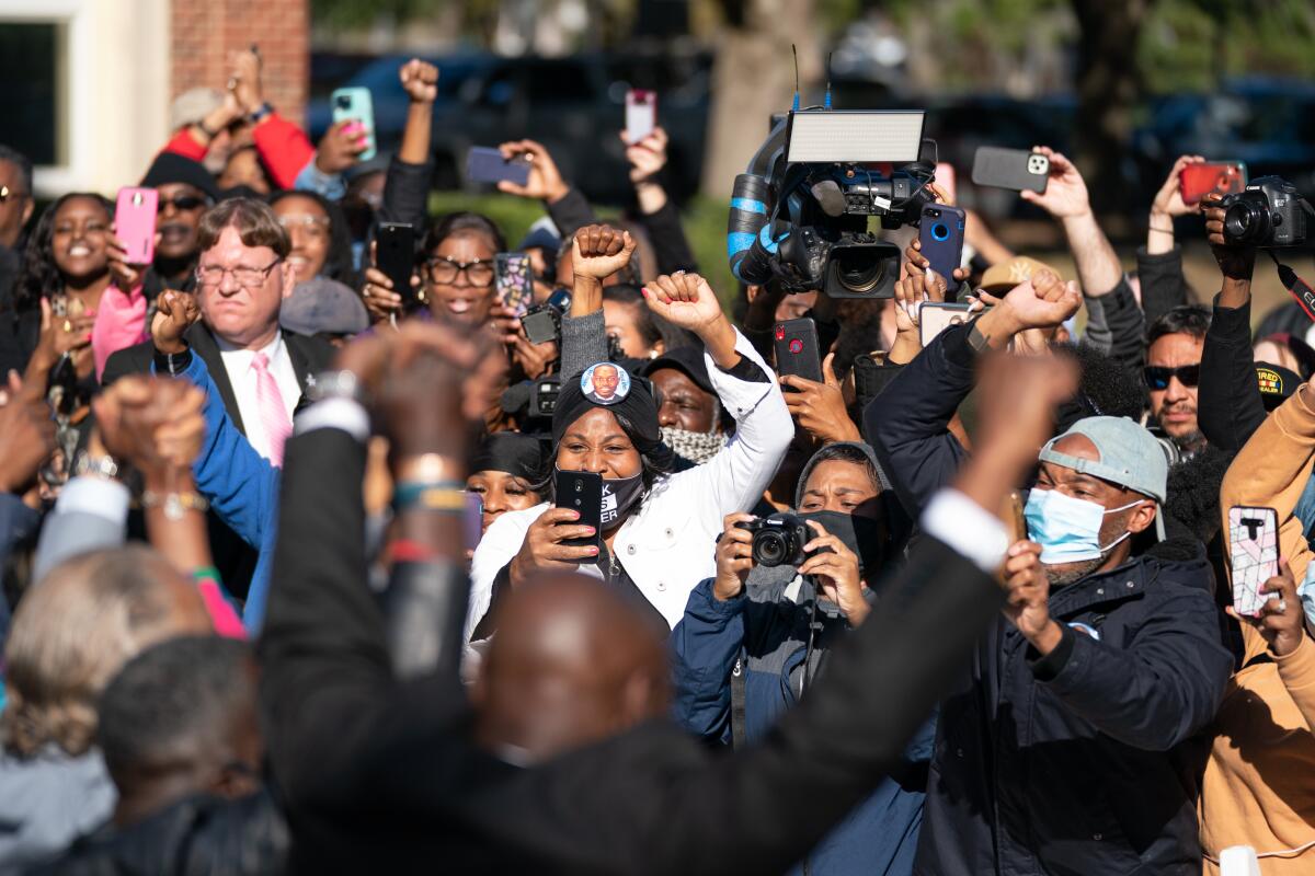 People raise their arms outdoors.