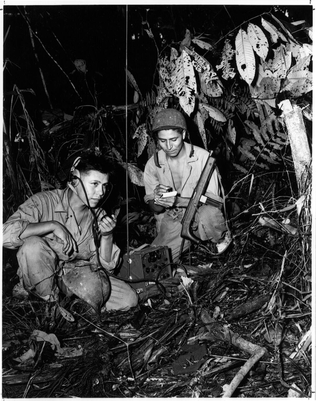 Navajo Code Talkers Henry Bake, Jr., and George Kirk, operate a radio in a jungle during World War II.