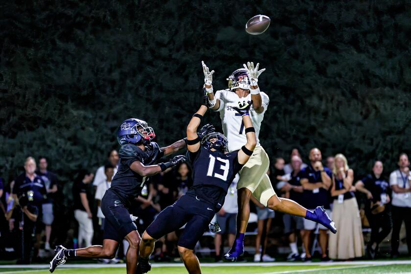 St. John Bosco's Madden Williams leaps to make catch between two Sierra Canyon defenders for 45-yard gain.