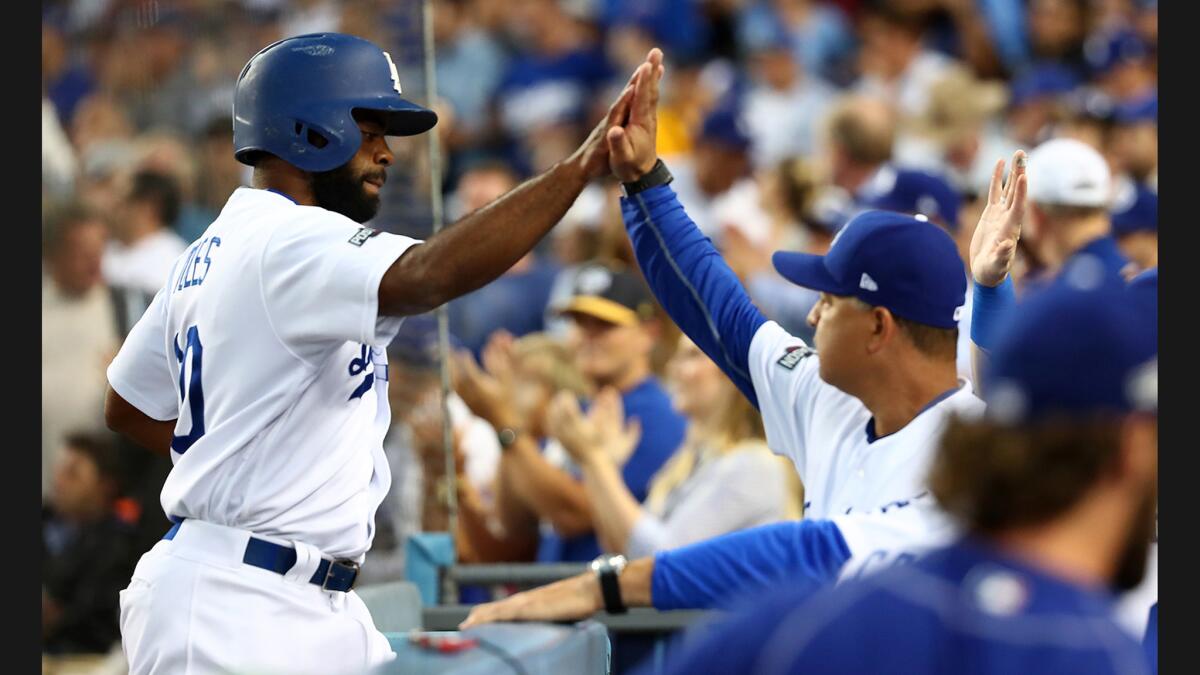 Andrew Toles is congratulated by manager Dave Roberts after scoring Dodgers first run.