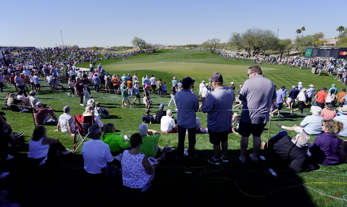 Fans circle the ninth hole as groups make their way up the fairway during the Phoenix Open golf tournament Thursday, Feb. 10, 2022, in Scottsdale, Ariz. (AP Photo/Darryl Webb)