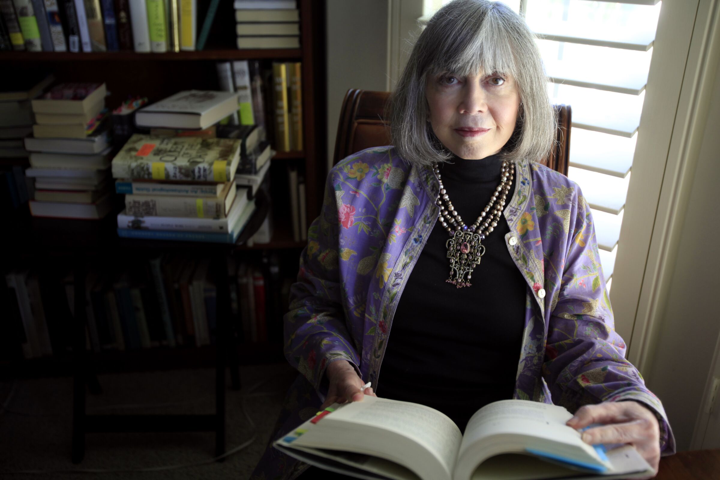 Anne Rice holds a book in her hands as she looks at the camera