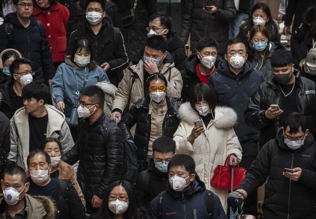 Chinese passengers, almost all wearing protective masks, arrive to board trains before the annual Spring Festival at a Beijing railway station on Thursday in Beijing. Medical experts have confirmed that the virus can be passed from human to human.