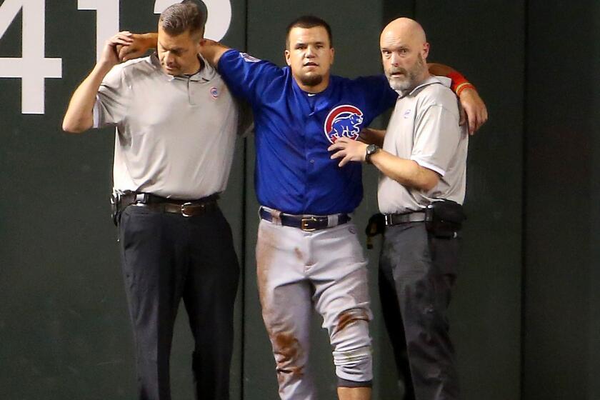 Cubs outfielder Kyle Schwarber is helped by team trainers after an injuring his left knee in a collsion with teammate Dexter Fowler on Thursday night in Phoenix.