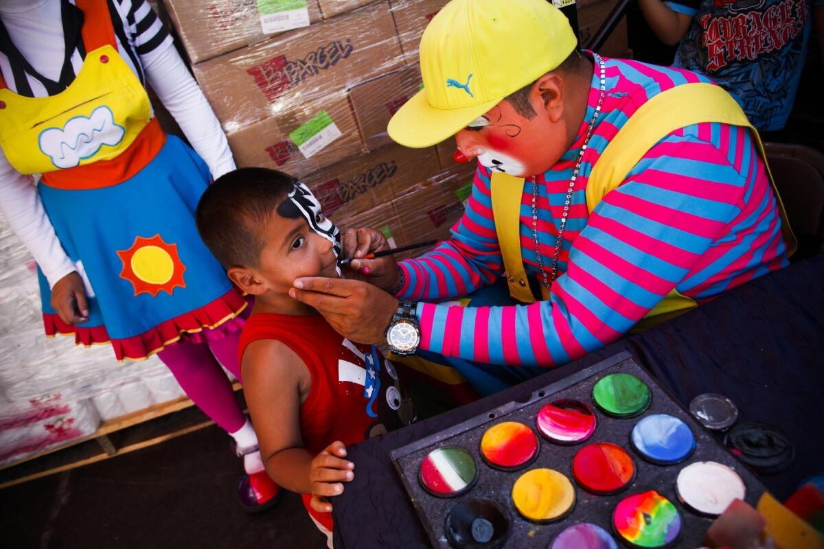 Jorge "Cookie the Clown" Camacho paints a child's face outside a pinata store in Los Angeles.