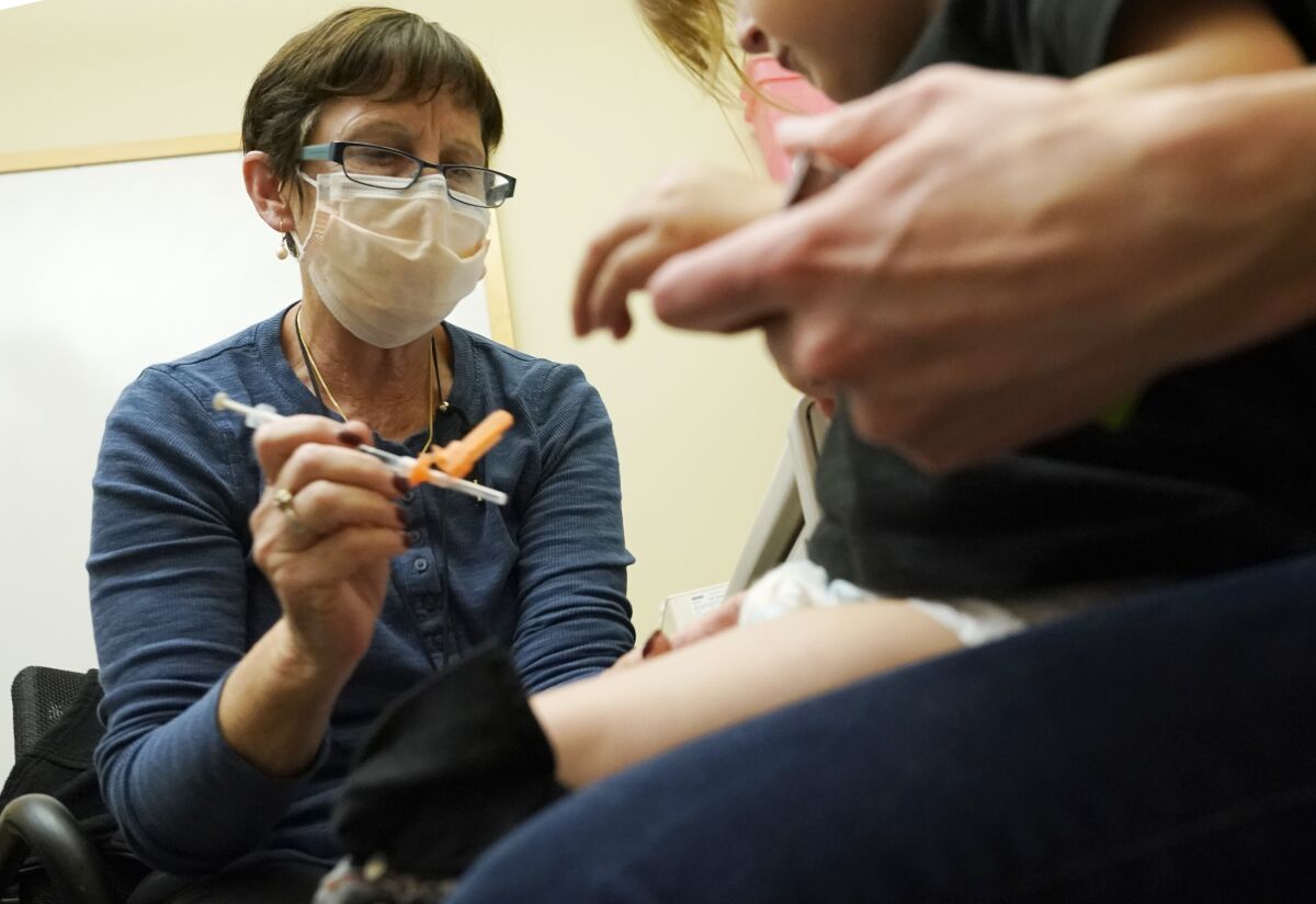 Deborah Sampson, a la izquierda, una enfermera en una clínica de la Universidad de Washington Medical Center en Seattle, aplica una inyección de la vacuna Pfizer COVID-19 a un niño de 20 meses de edad, el 21 de junio de 2022, en Seattle. (AP Foto/Ted S. Warren, archivo)