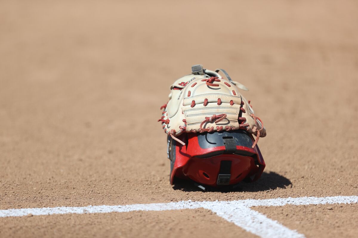 A softball catcher's helmet and glove on the field.