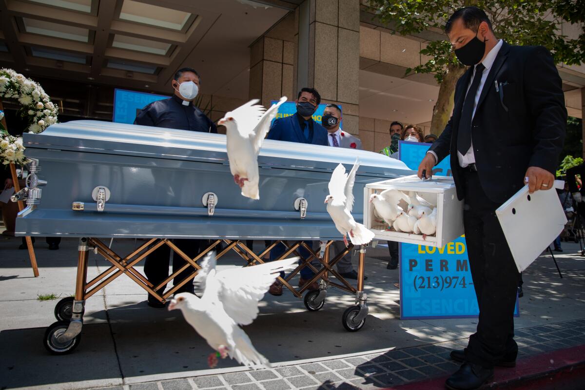 Luis Ortiz, a life agent with Continental Funeral Home, releases doves in downtown Los Angeles.