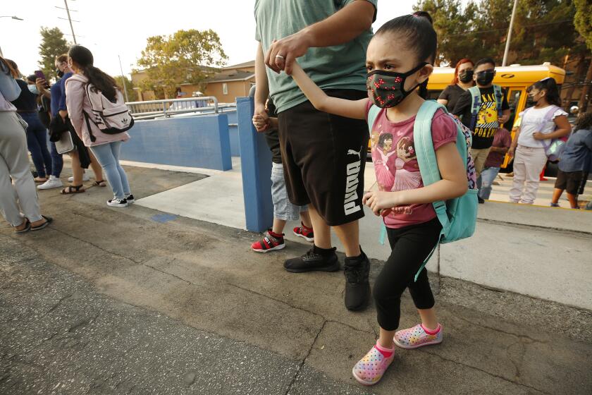 HARBOR CITY, CA - AUGUST 16: Kindergarten student Natalia Bayoumi holds the hand of her father Amir Bayoumi as he walks Natalia and her first grade brother Adam to the front door of Normont Elementary School on the first day of in class instruction on August 16, as LAUSD officials welcome students, teachers, principals, at various school sites across Los Angeles. For the younger students it will be their first time in a classroom. Normont Elementary on Monday, Aug. 16, 2021 in Harbor City, CA. (Al Seib / Los Angeles Times).